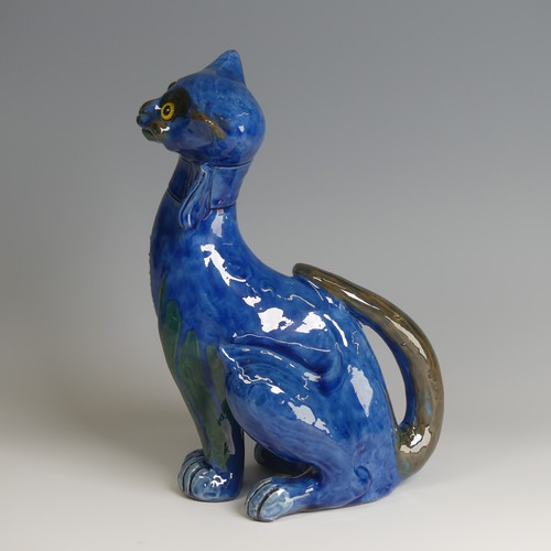 56 - A C. H. Brannam pottery figure of a Cat, with wide grin, sporting a butterfly collar, blue ground pa... 