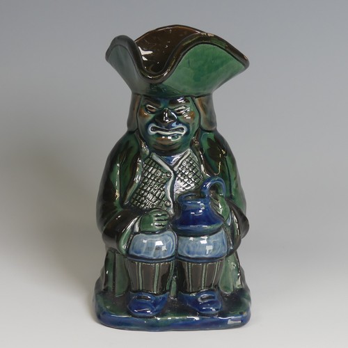 63 - A C. H. Brannam pottery Character Jug, decorated as a seated man with jug in hand in tones of blue, ... 