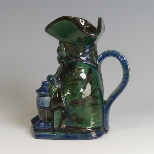 63 - A C. H. Brannam pottery Character Jug, decorated as a seated man with jug in hand in tones of blue, ... 