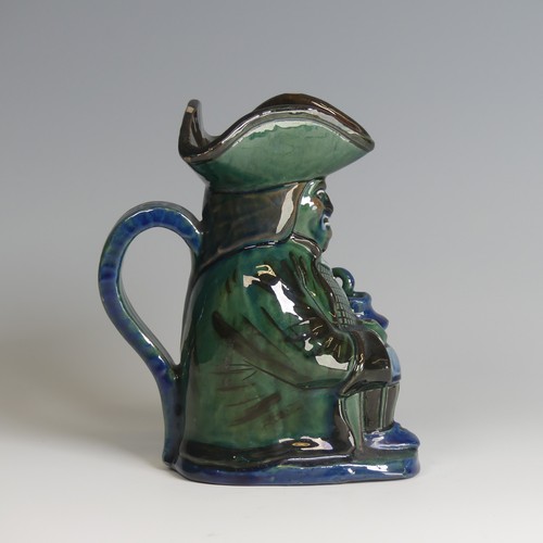 63 - A C. H. Brannam pottery Character Jug, decorated as a seated man with jug in hand in tones of blue, ... 