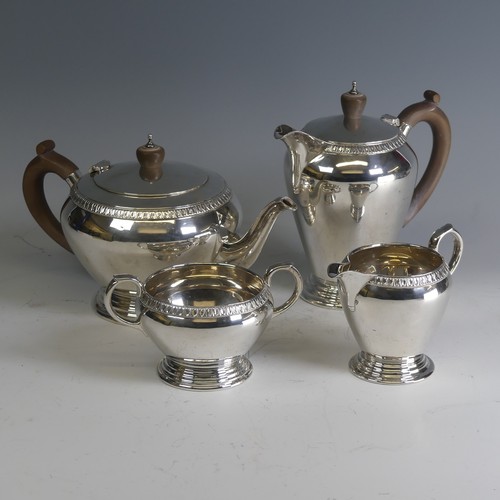 A George VI silver four piece Tea Set, by Wakely & Wheeler, hallmarked London 1948, of circular form, the teapot and hot water pot with wooden handles and finials, the teapot 15cm high, gross total weight 57ozt (4)