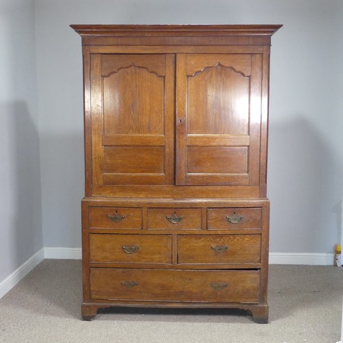 A Georgian oak housekeepers Cupboard, the moulded cornice over moulded doors enclosing shelves, raised on drawers and shaped bracket feet, W 135 cm x H 199 cm x D 54.5 cm.