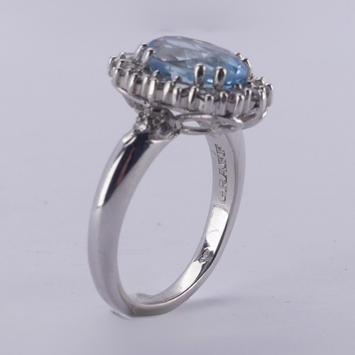  An aquamarine and diamond cluster Ring, the oval facetted aquamarine approx. 9.68mm long, within a s... 