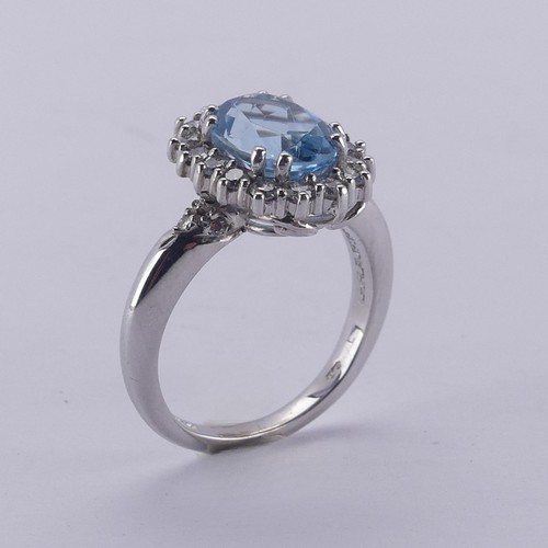  An aquamarine and diamond cluster Ring, the oval facetted aquamarine approx. 9.68mm long, within a s... 