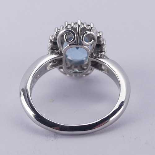  An aquamarine and diamond cluster Ring, the oval facetted aquamarine approx. 9.68mm long, within a s... 