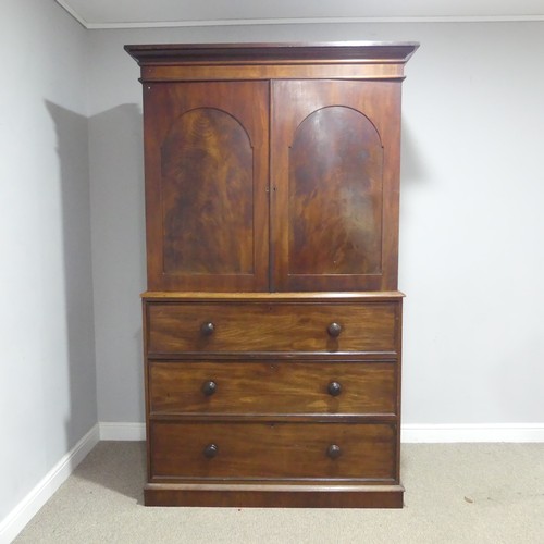 A George III mahogany Linen Press, the moulded cornice over large panel arched doors enclosing three slides, raised on base of three drawers and plinth, W 131 cm x H 216 cm x D 57 cm.