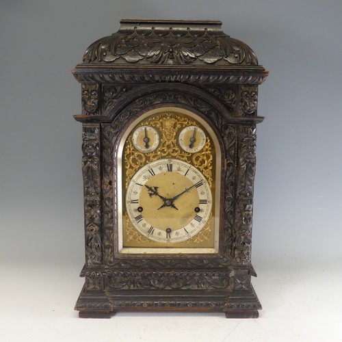 A Winterhalder & Hofmeier German bracket mantel Clock, retailed by Mappin & Webb Paris, the heavily carved oak case with foliage and 'Green Man' above caryatids, the triple fusee movement with pull repeat chiming on five coiled gongs from a pin-barrel, the 16cm silvered chapter ring having Roman numeral hours and Arabic minutes, stamped 'Mappin & Webb, Paris', beneath two silvered subsidiary Slow/Fast and Chime/Silent rings, the dial with matted centre and decorated with gilt-metal Rococo spandrels, the movement stamped 'W&H Sch', W 35 cm x H 54 cm x D 25.5 cm.
