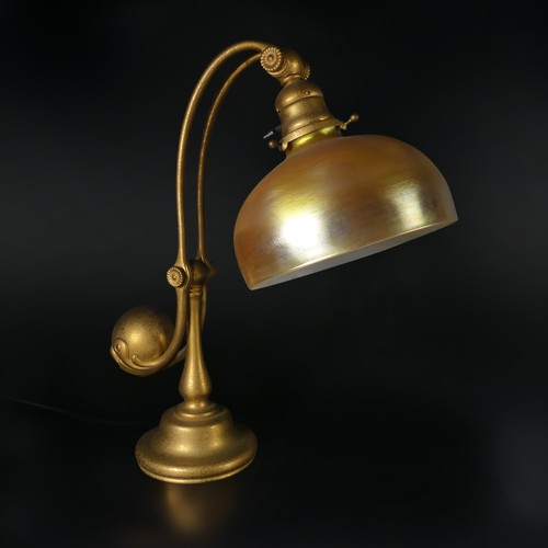 Tiffany Studios; A counter-balance patinated gilt bronze desk Lamp, with ‘favrile’ glass shade, c. 1905, the shade signed with L.C.T and the base ‘TIFFANY STUDIOS NEW YORK 417’, height 40 cm, shade diameter 17.75 cm. 
