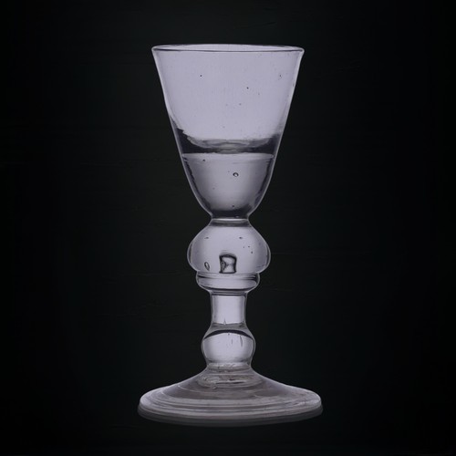 55 - An antique heavy baluster Dram Glass, the conical bowl with thick well, double-knopped stem and flar... 