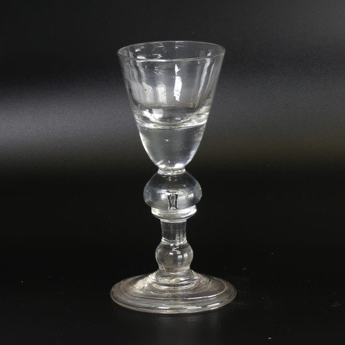 55 - An antique heavy baluster Dram Glass, the conical bowl with thick well, double-knopped stem and flar... 
