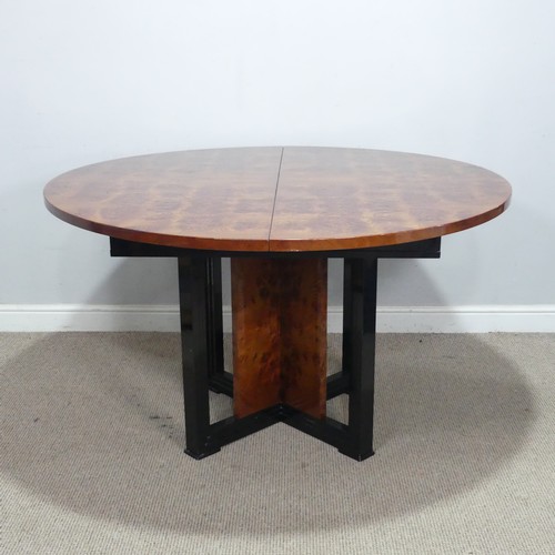 33 - An Art Deco 1970s simulated burr walnut dining Table, the circular extending top raised on ebonised ... 