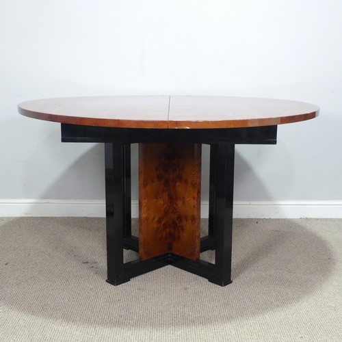 33 - An Art Deco 1970s simulated burr walnut dining Table, the circular extending top raised on ebonised ... 
