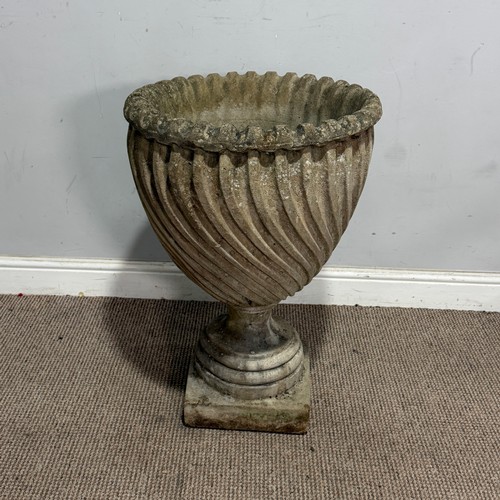 180 - A weathered reconstituted stone garden Urn, in a swirled fluted form, raised on a column plinth base... 