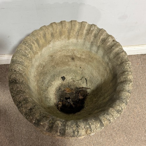 180 - A weathered reconstituted stone garden Urn, in a swirled fluted form, raised on a column plinth base... 