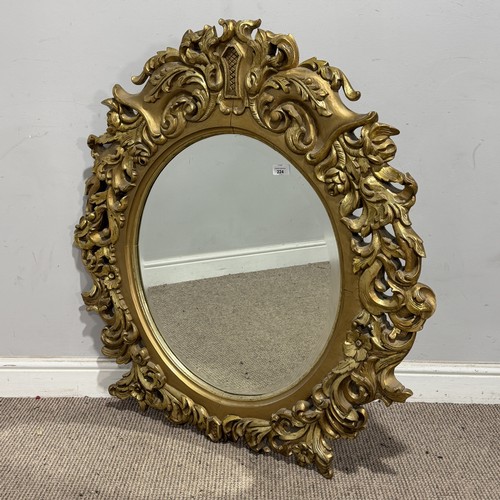 224 - A Louis XVI style gilt painted wall Mirror, the oval bevelled mirror plate in a profusely decorated ... 