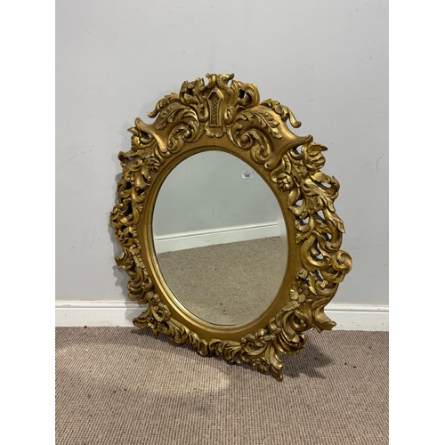 224 - A Louis XVI style gilt painted wall Mirror, the oval bevelled mirror plate in a profusely decorated ... 