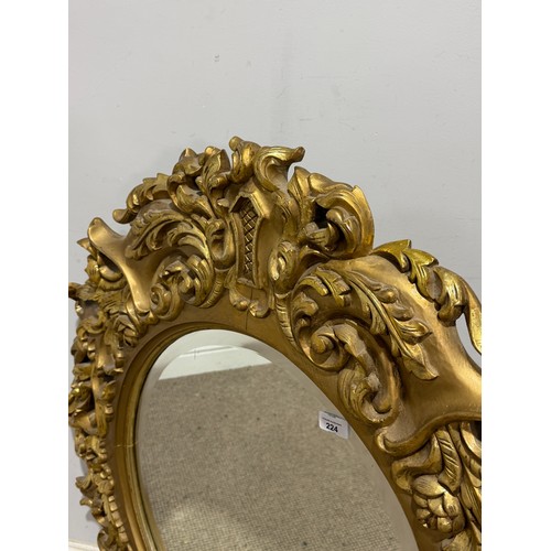 224 - A Louis XVI style gilt painted wall Mirror, the oval bevelled mirror plate in a profusely decorated ... 