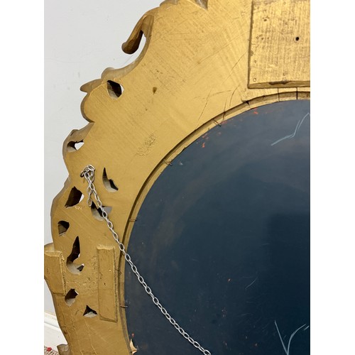 224 - A Louis XVI style gilt painted wall Mirror, the oval bevelled mirror plate in a profusely decorated ... 