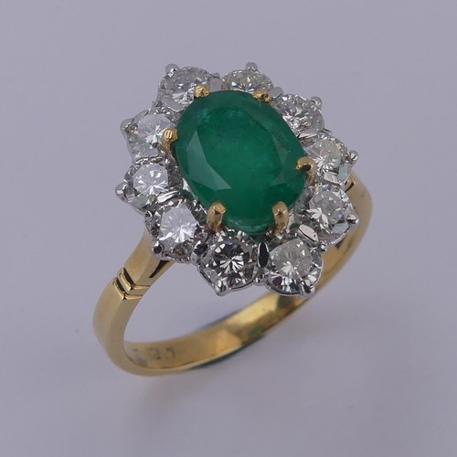 An emerald and diamond cluster Ring, the central oval facetted emerald approx. 9.4mm x 7.7mm, claw set above a surround of ten brilliant cut diamonds, each approx. 0.2ct, the cluster overall 26.7mm x 15.2mm, on an 18ct yellow gold shanks, London import marks for 1995, Size S, 5.9g.