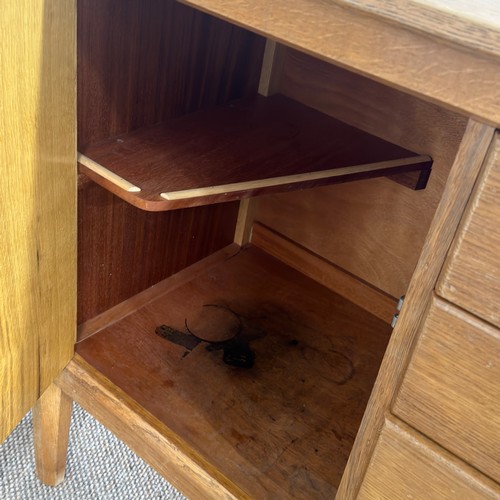 13 - A mid-20th century Cotswold School light oak Sideboard, by Heals of London, the central drop of four... 