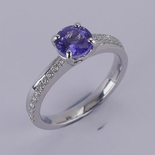 A tanzanite and diamond Ring, the central circular facetted tanzanite approx. 6.13mm diameter, four claw set above double banded shoulders, one band set with eleven brilliant cut diamonds on either side, total diamond weight approx. 0.22ct, all mounted in 18ct white gold, hallmarked London 2014, Size M, 4g.