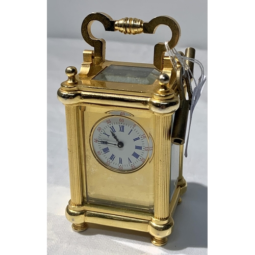 347 - UNNAMED MINIATURE BRASS TRAVEL CLOCK WITH KEY, CIRCULAR WHITE DIAL WITH BLUE ROMAN NUMERALS AND RED ... 