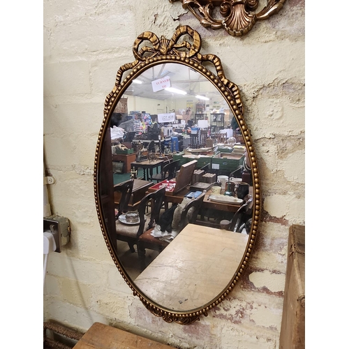 408 - AN OVAL GILDED RIBBON AND BALL WALL MIRROR