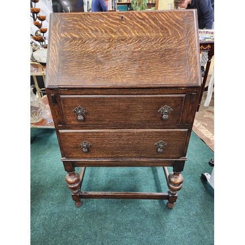 207 - SMALL OAK DROP FRONT BUREAU WITH TWO DRAWERS ON RAISED LEGS WITH STRETCHERS