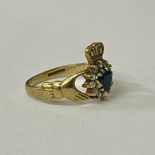 259 - A 9CT YELLOW GOLD 'CLADDAGH' RING - A CENTRAL HEART SHAPED SAPPHIRE WITH CZ'S SURROUND - H/M BIRMING... 