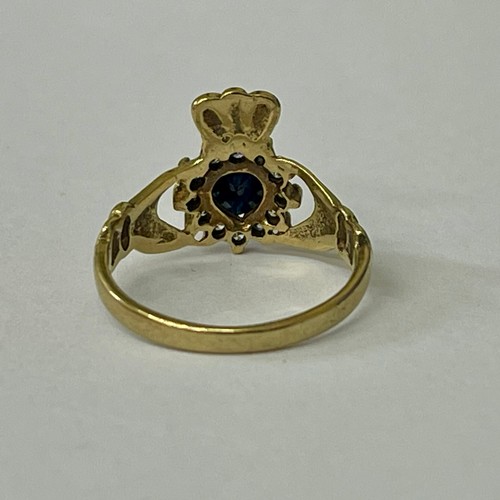 259 - A 9CT YELLOW GOLD 'CLADDAGH' RING - A CENTRAL HEART SHAPED SAPPHIRE WITH CZ'S SURROUND - H/M BIRMING... 