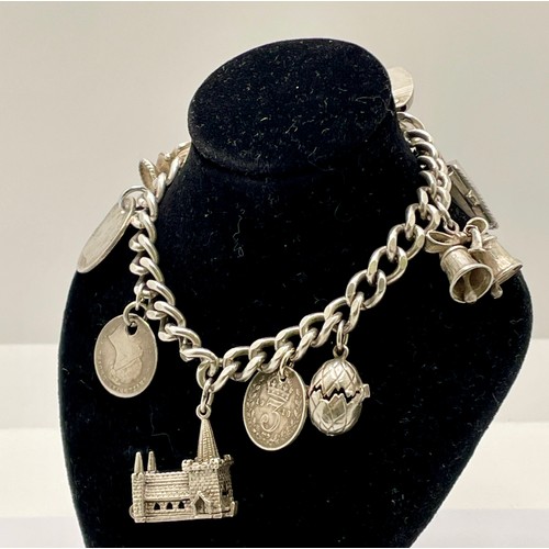 370 - A  SILVER CURB LINK BRACELET WITH 9 SILVER CHARMS INCL. PADLOCK, BIBLE, CHURCH, PAIR OF BELLS, HINGE... 