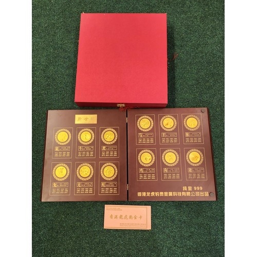 322 - A BOXED BOOKLET CONTAINING 12 GOLD PLATED CHINESE COINS DEPICTING THE CHINESE YEARS - IN WOODEN FOLD... 