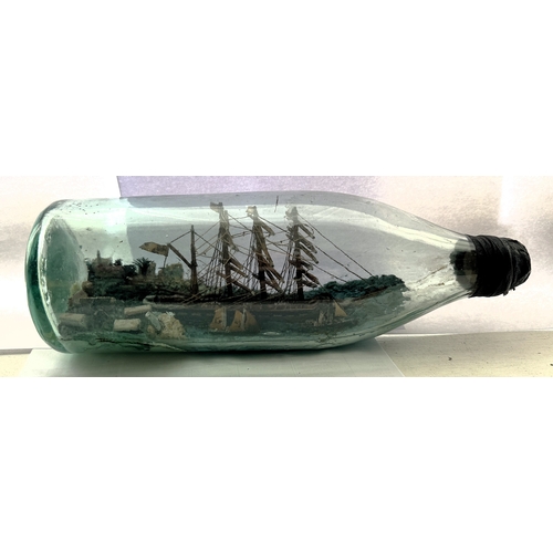 371 - A VINTAGE SHIP IN BOTTLE DIORAMA SHOWING A FOUR MASTED SHIP WITH TWO SMALLER VESSELS LEAVING A PORT ... 