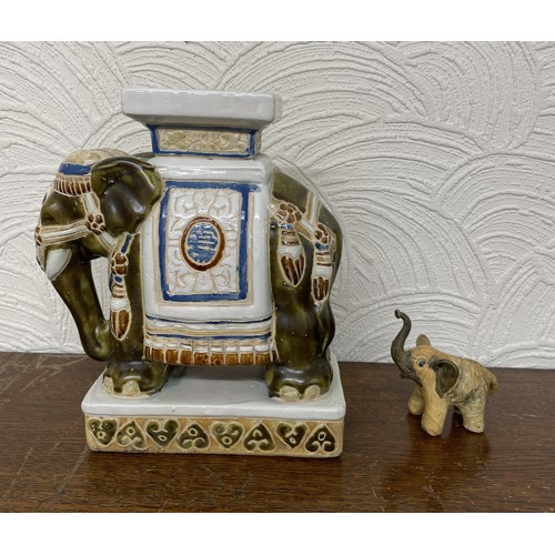 402 - X2 ELEPHANT FIGURINES - ONE CARVED WOODEN ELEPHANT AND ONE ORNATE CERAMIC BLUE, WHITE AND RED STANDI... 