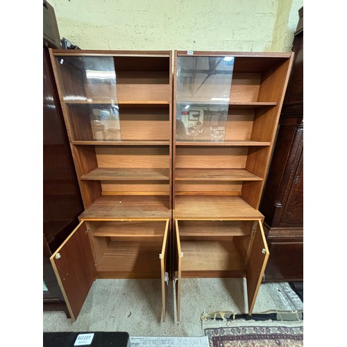 358 - PAIR OF TEAK SLIDING DOOR FOUR SHELF BOOK CASES WITH CUPBOARD BASE