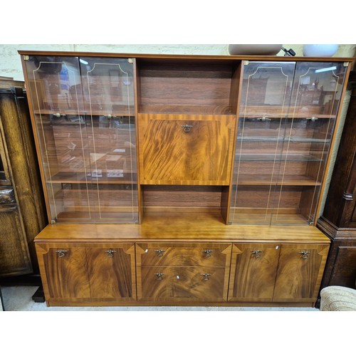 239 - A GLAZED TEAK VENEER DISPLAY CABINET WITH DROP FRONT, TWO DRAWERS, FLANKED EITHER SIDE BY DOUBLE DOO... 