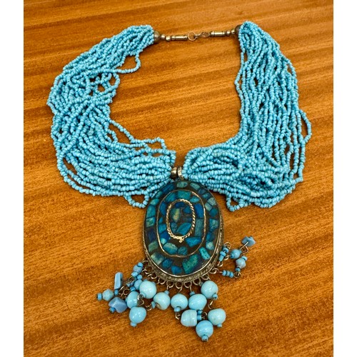 430 - A GLASS BEAD TURQUOISE STRANDED NECKLACE WITH A TURQUOISE INLAID SILVER METAL PENDANT OF OVAL FORM -... 