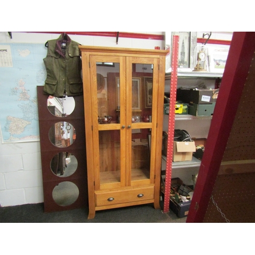 1066 - A light oak glazed two door cabinet with single base drawer.  185cm x 90cm x 38cm