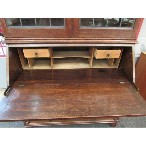 1105 - An Edwardian oak bookcase bureau, the lead glazed two doors and height adjustable shelves over a fit... 