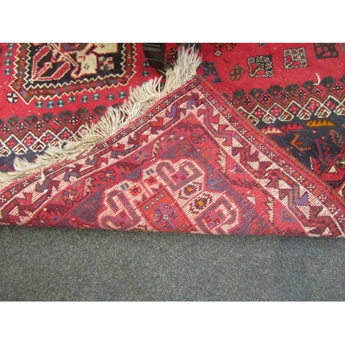 1539 - A red ground machine woven wool, geometric design rug with tasselled end, 265cm x 180cm