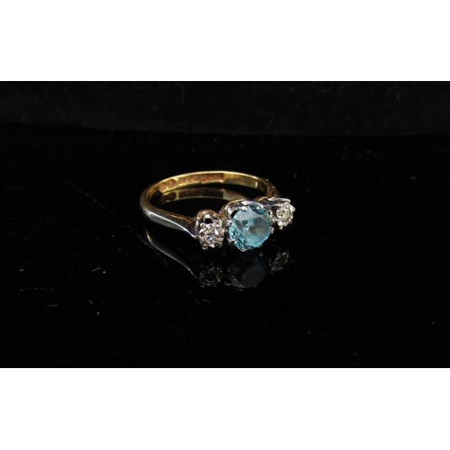 5076 - An 18ct gold three stone ring, central pale blue stone flanked by 0.10ct approx diamonds. Size K/L, ... 