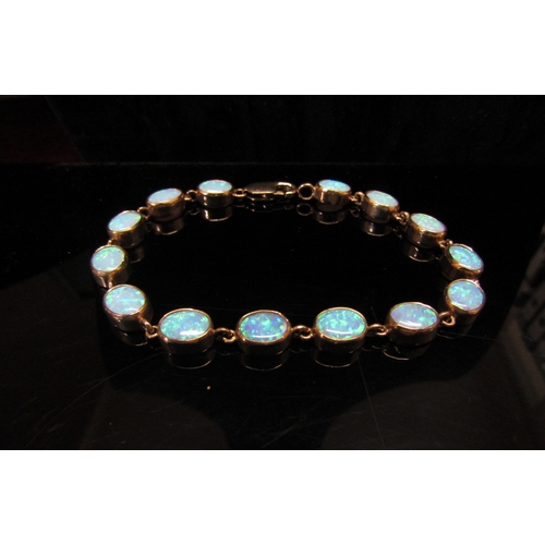 5113 - An opal bracelet, with fourteen oval opal links, stamped 375, 19cm long, 11.8g