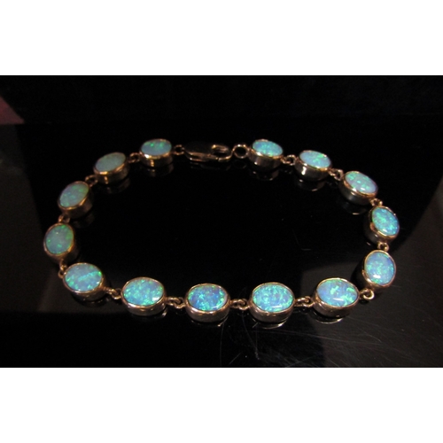 5113 - An opal bracelet, with fourteen oval opal links, stamped 375, 19cm long, 11.8g