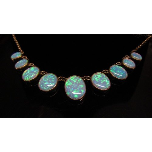 5114 - A 9ct gold necklace with nine graduated oval opal drops, 44cm long, 10.7g