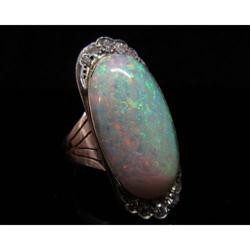 5186 - An opal and diamond ring, the central oval cabochon opal 23mm x 12.4mm x 5.77mm, estimated weight 9.... 