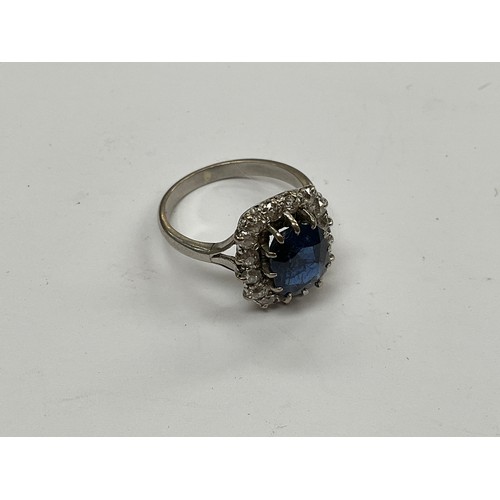 8097 - A sapphire and diamond ring, the central sapphire 9mm x 7mm, framed by 16 round cut diamonds, shank ... 