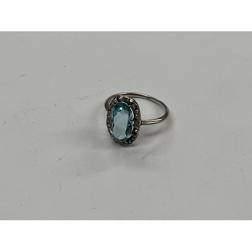 8098 - An aquamarine and diamond ring, the oval aqua 12mm x 7mm, framed by small diamonds in unmarked white... 