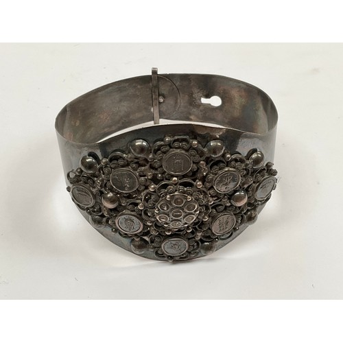 8101 - A white metal bangle with pictorial rounders and foliate scrolled decoration