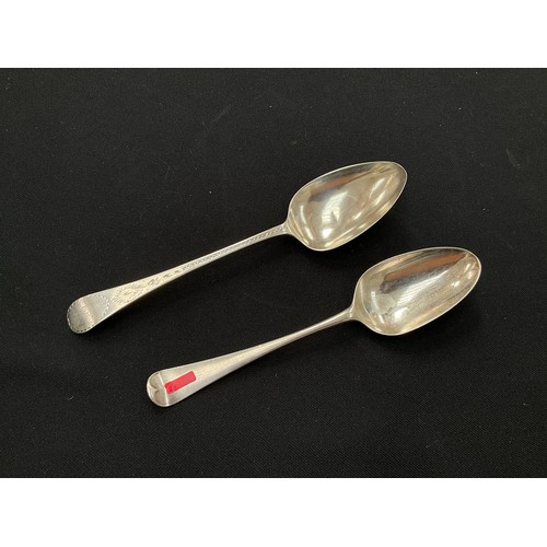 8223 - Two Georgian silver serving spoons, one with bright cut detail and monogrammed handles, 108g