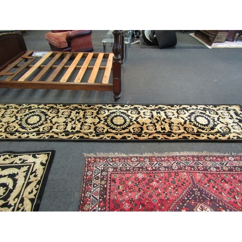 1024 - A Chinese black wool runner rug with gold decoration, 372cm x 77cm